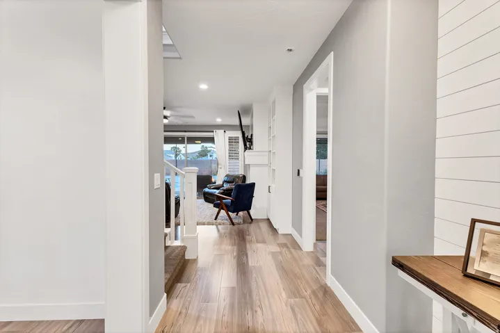 Wood-finish flooring throughout, bright recessed lighting, and white shiplap wall accent