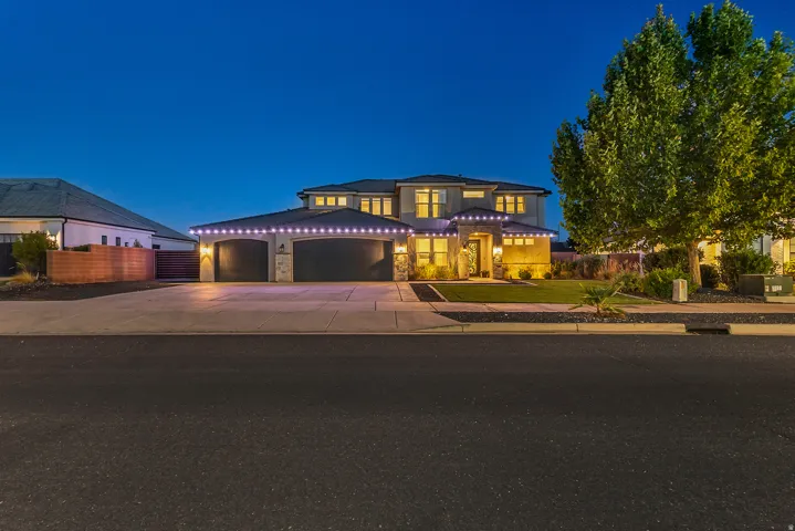 Two-story exterior with stone accents, an attached three-car garage, mature landscaping, and a concrete driveway
