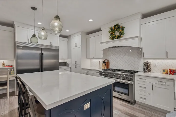 White cabinetry and a dark blue kitchen island with a light countertop
