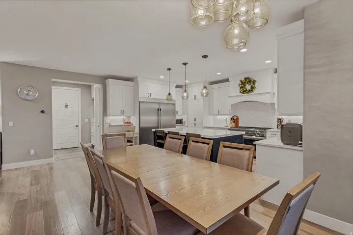 Recessed lighting, wood-finish flooring, white cabinetry, tile backsplash, and stainless steel appliances