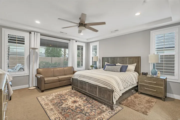 Recessed lighting, ceiling fan, crown molding, white window shutters, and wood-finish nightstands