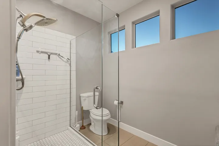 Enclosed shower with white subway tile and hexagonal floor tile, featuring a dual shower head system
