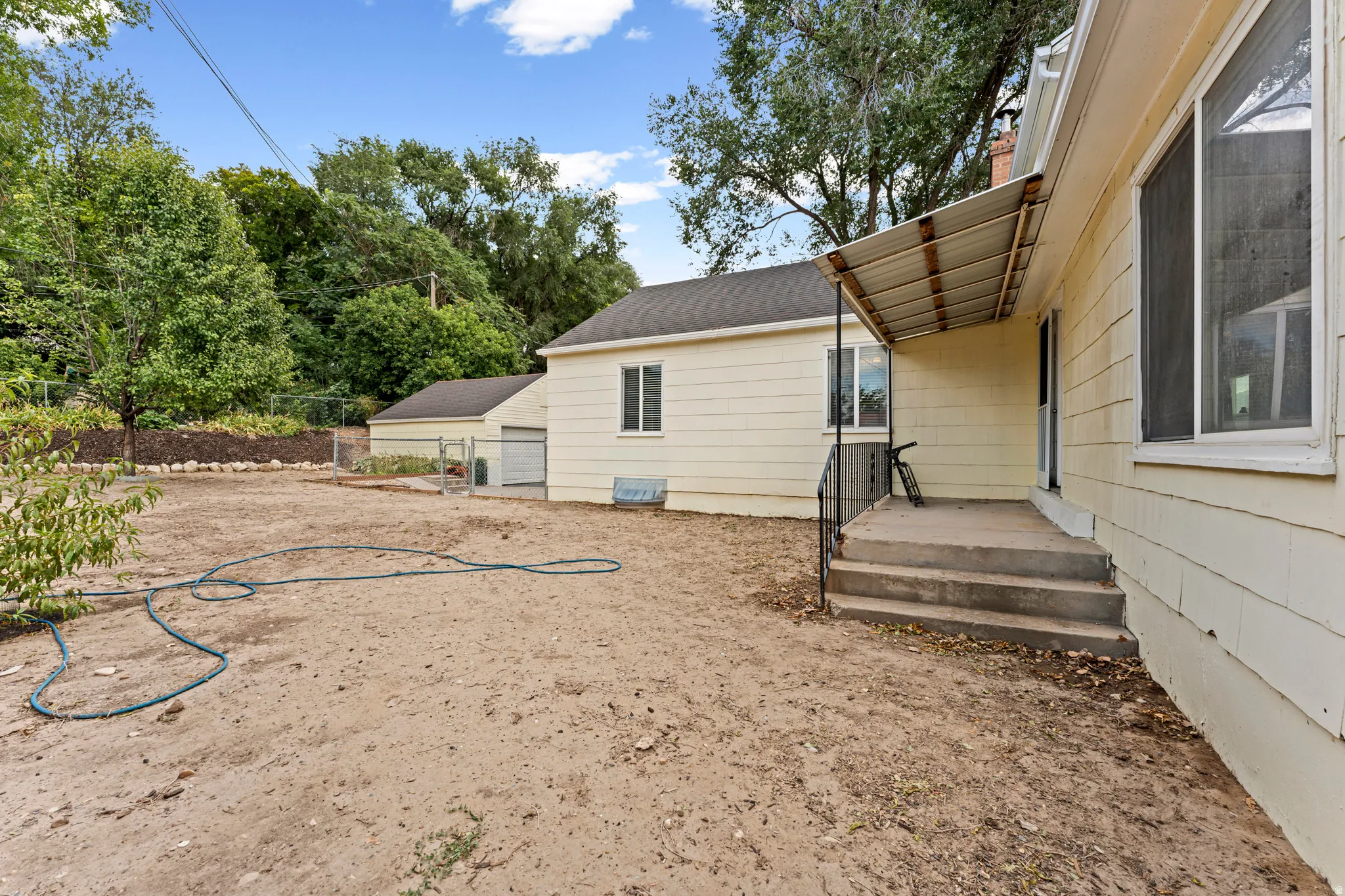 Rear exterior with covered concrete patio, multiple windows, and a detached structure