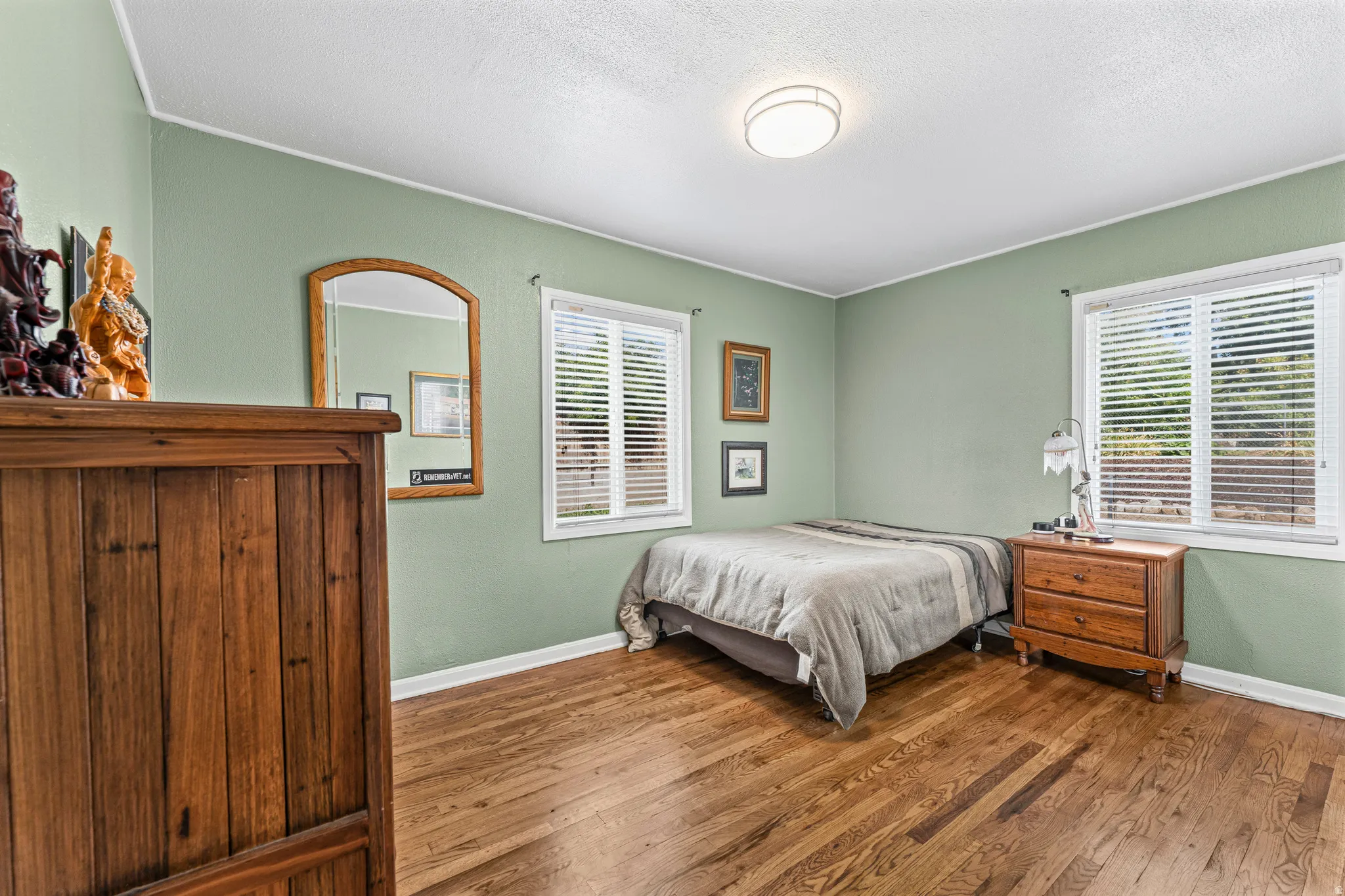Hardwood flooring, two windows with blinds, and a ceiling-mounted light fixture