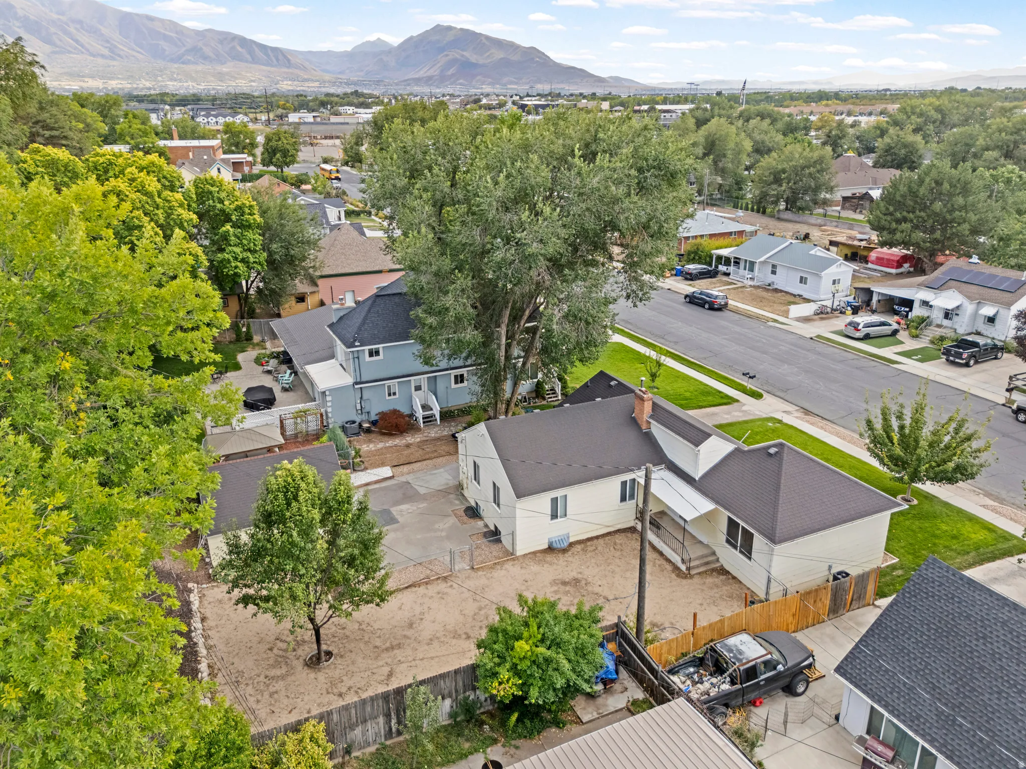 Neighborhood setting featuring mature trees, paved streets, and distant mountains