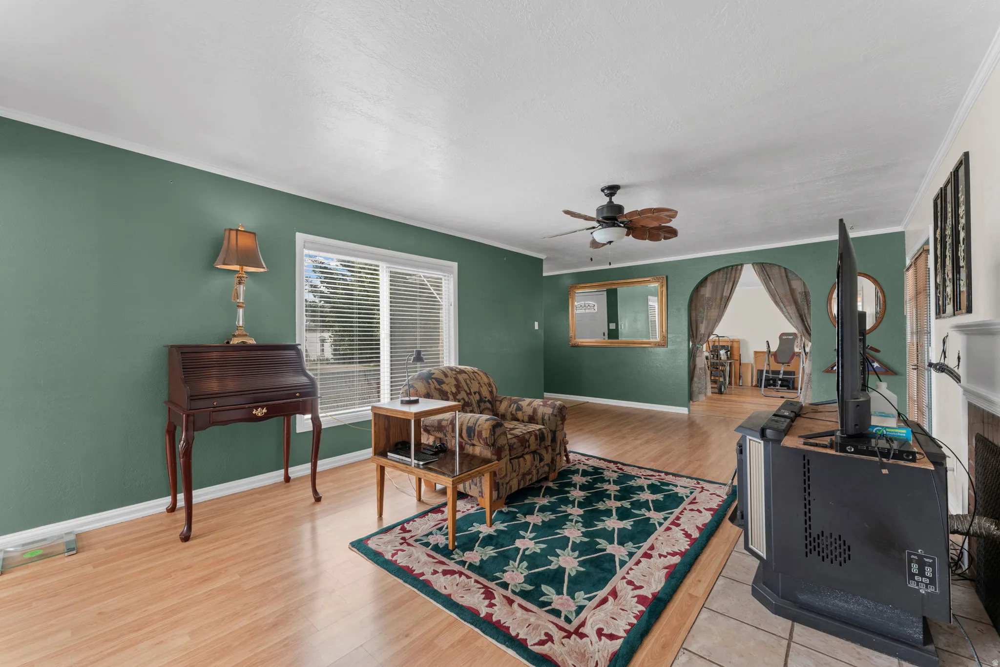 Hardwood-finish flooring throughout, ceiling fan, and arched entryway