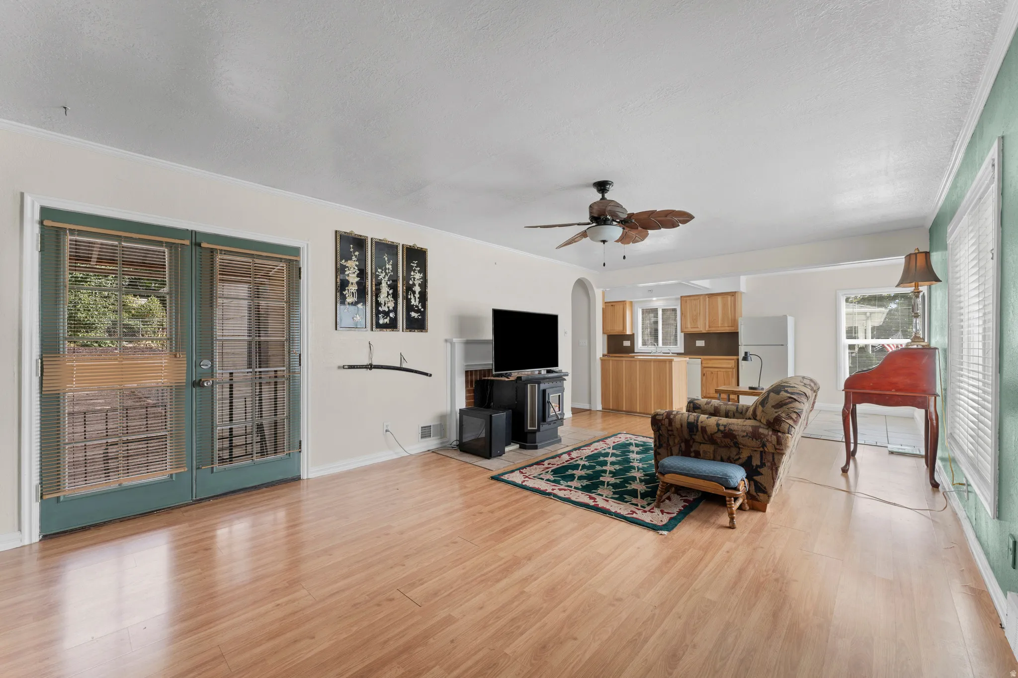 Hardwood-finish flooring, built-in fireplace, ceiling fan with light fixture, and French doors with privacy blinds