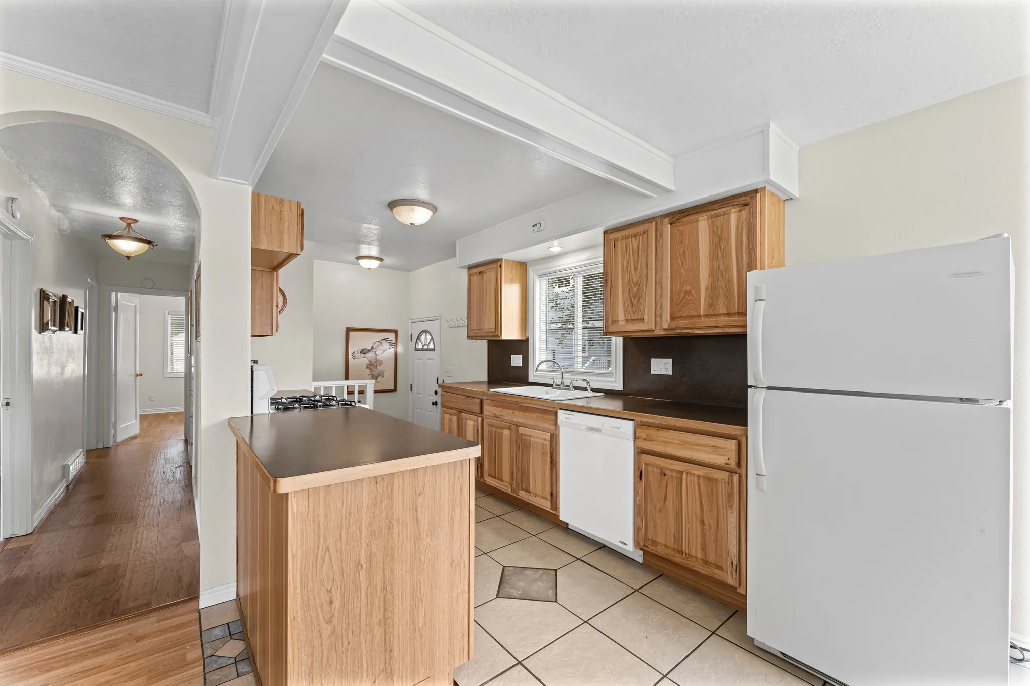 Kitchen featuring wood-finish cabinetry, a gas range, and a white refrigerator