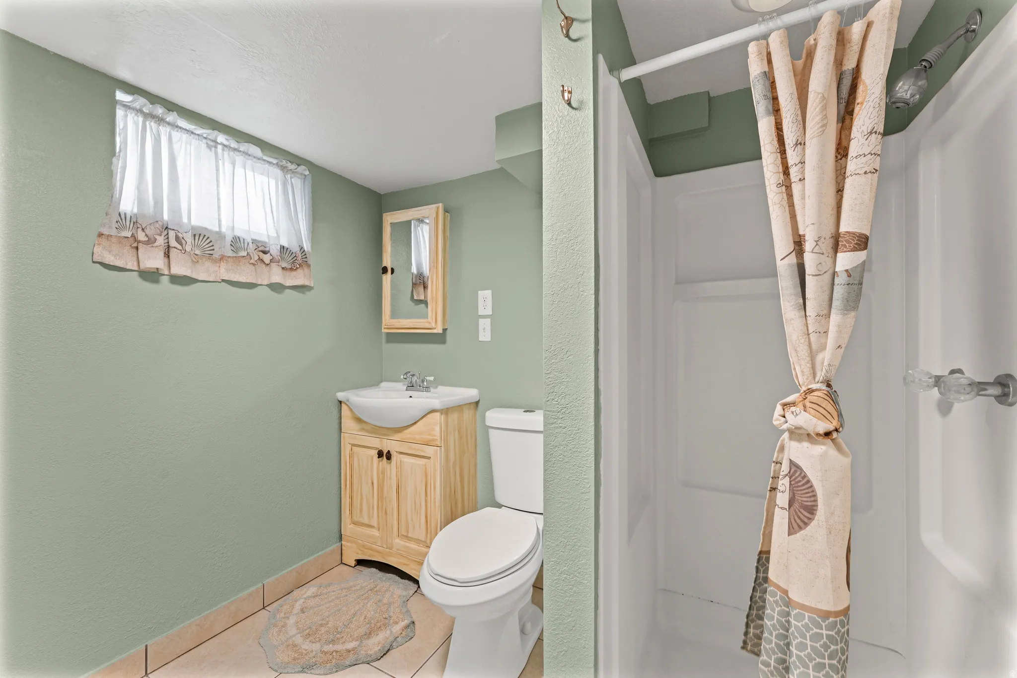 Compact bathroom featuring a shower stall, wood-finish vanity with an integrated sink, and a mirrored medicine cabinet