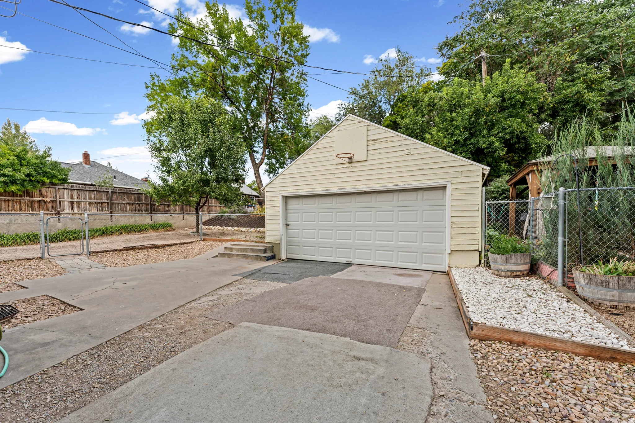 Detached garage with a paneled door, concrete driveway, and gravel beds