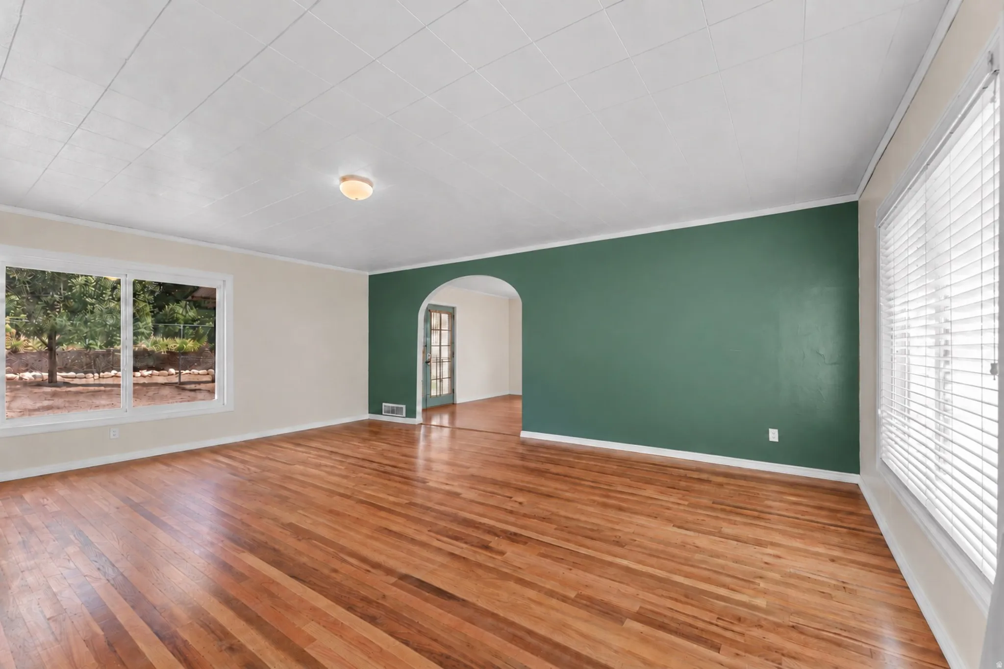Hardwood flooring, painted walls, an arched doorway, and windows with blinds