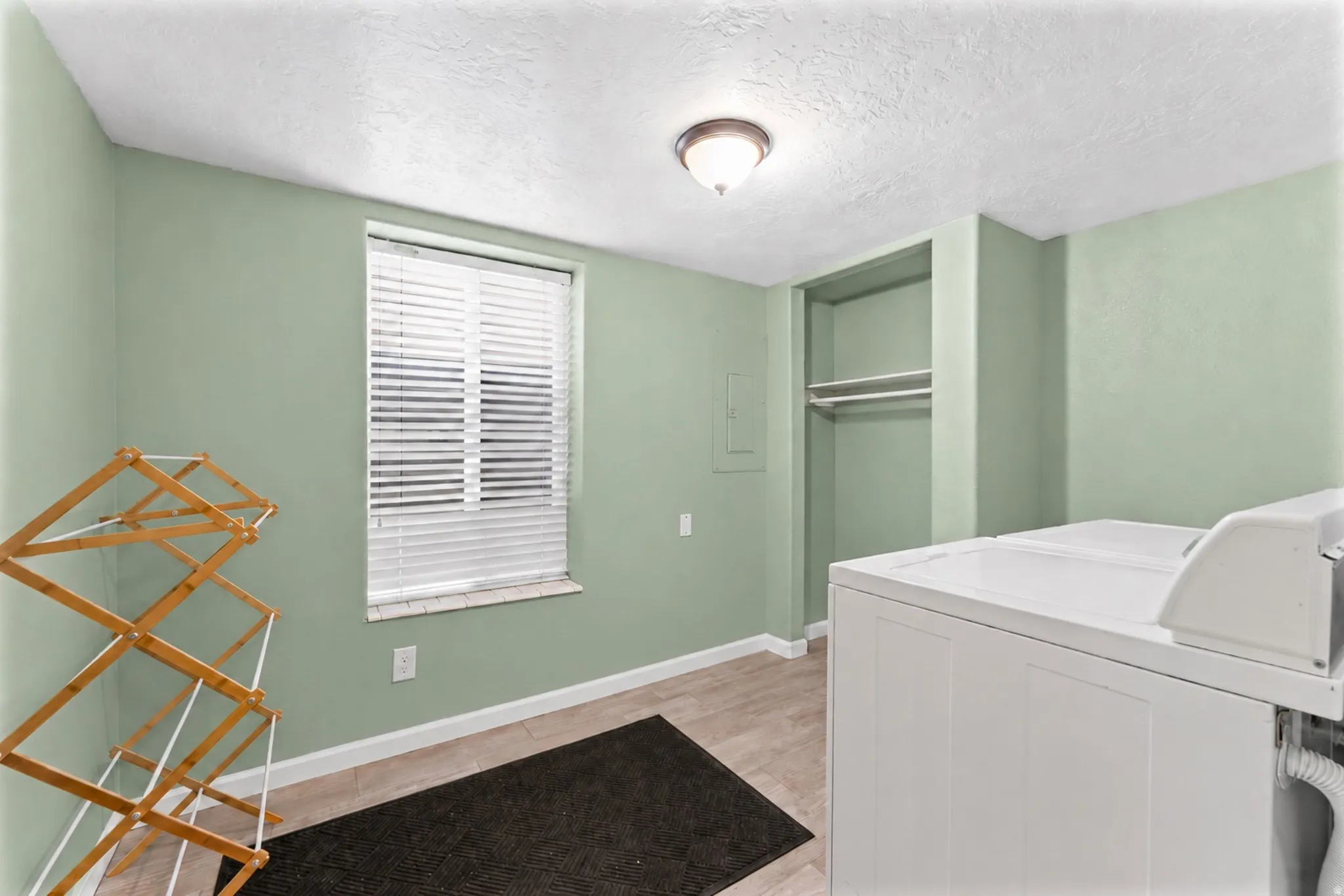 Window with blinds, built-in shelving, wood-finish flooring, and overhead lighting