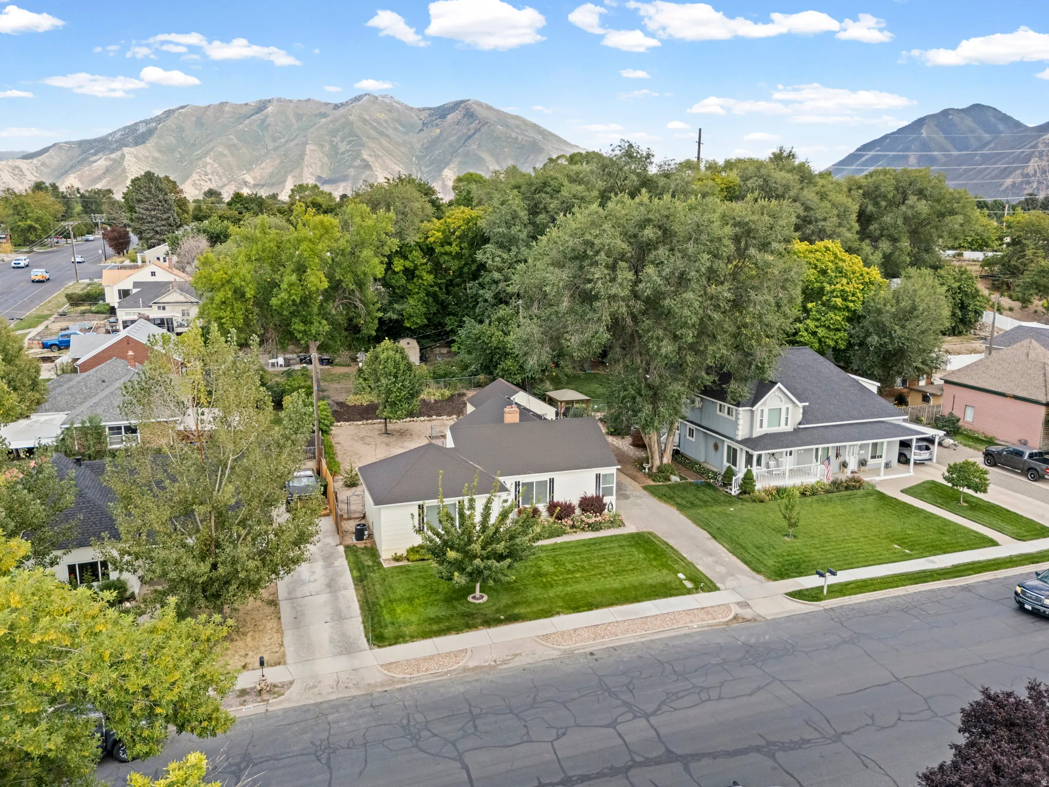 Expansive mountain backdrop, established neighborhood setting, mature trees, manicured lawns, and paved roads