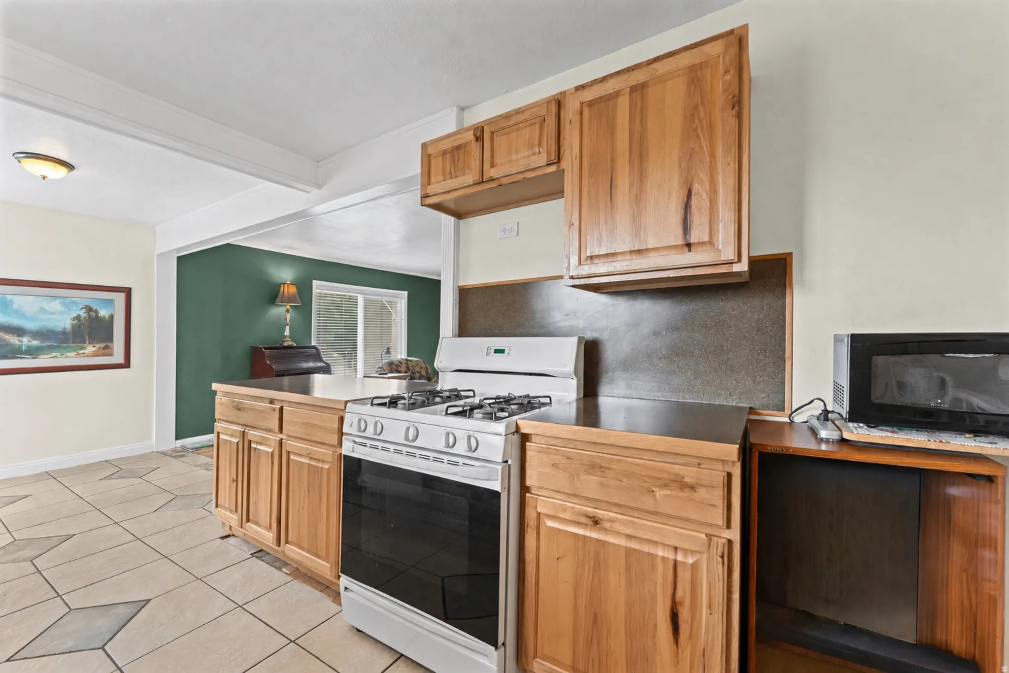 Kitchen featuring wood cabinetry, a gas range, and tile flooring
