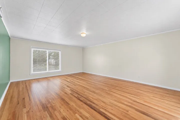 Hardwood flooring, neutral wall tones, window with horizontal blinds, overhead lighting fixture, and white ceiling