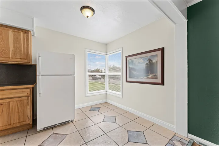 Corner windows, tile flooring with geometric accents, wood-finish cabinetry, and a flush-mount ceiling light