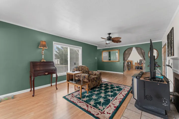 Hardwood-finish flooring throughout, ceiling fan, and arched entryway