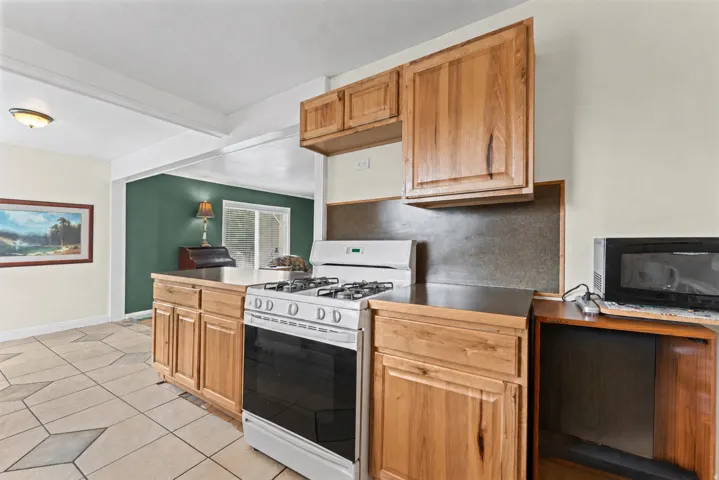 Kitchen featuring wood cabinetry, a gas range, and tile flooring