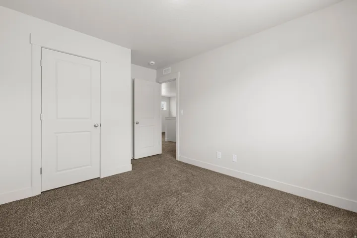 Neutral wall paint, textured carpet flooring, recessed ceiling lighting, and white two-panel interior doors