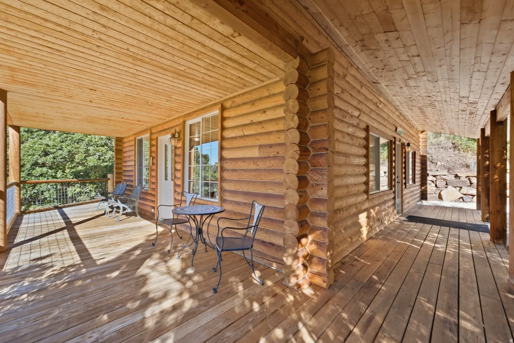 Expansive wood deck with a full-length covered porch and log cabin-style exterior