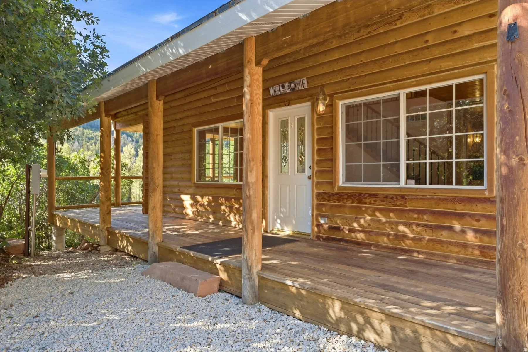 Wood-paneled exterior featuring a covered porch, wood plank decking, and a white entry door with decorative glass inserts