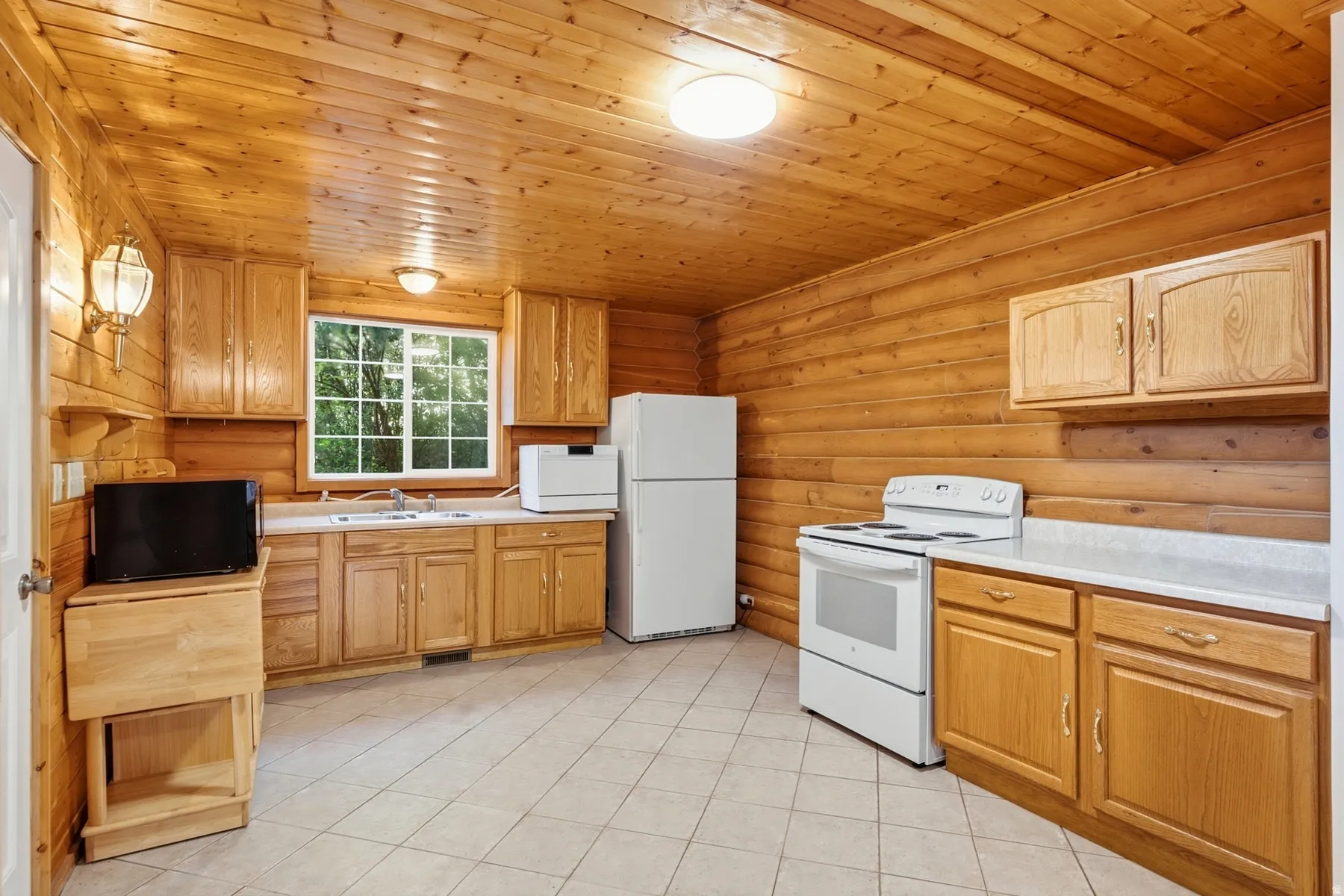Wood paneling and ceiling, white appliances, light wood-finish cabinetry, and white countertops