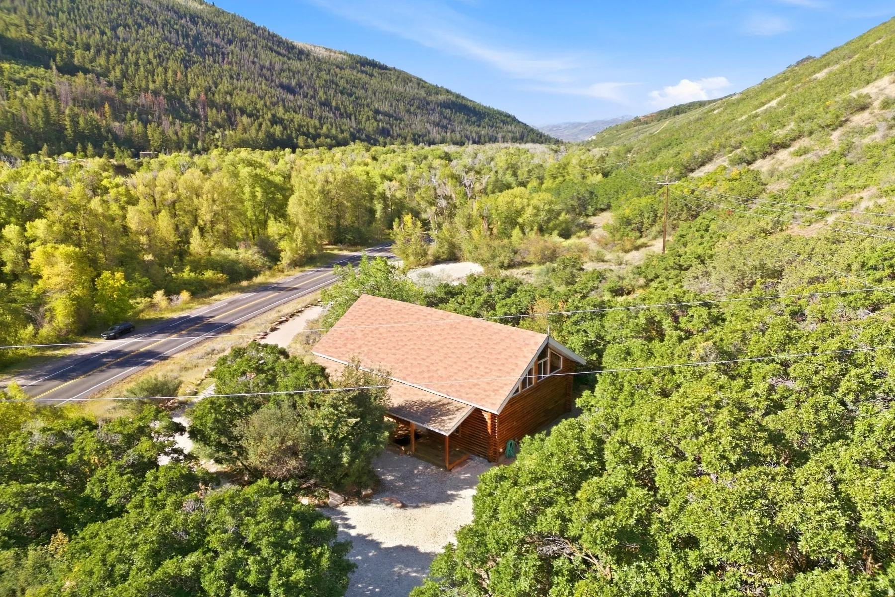 Wood-sided cabin-style residence with a distinct brown shingle roof, set among mature trees