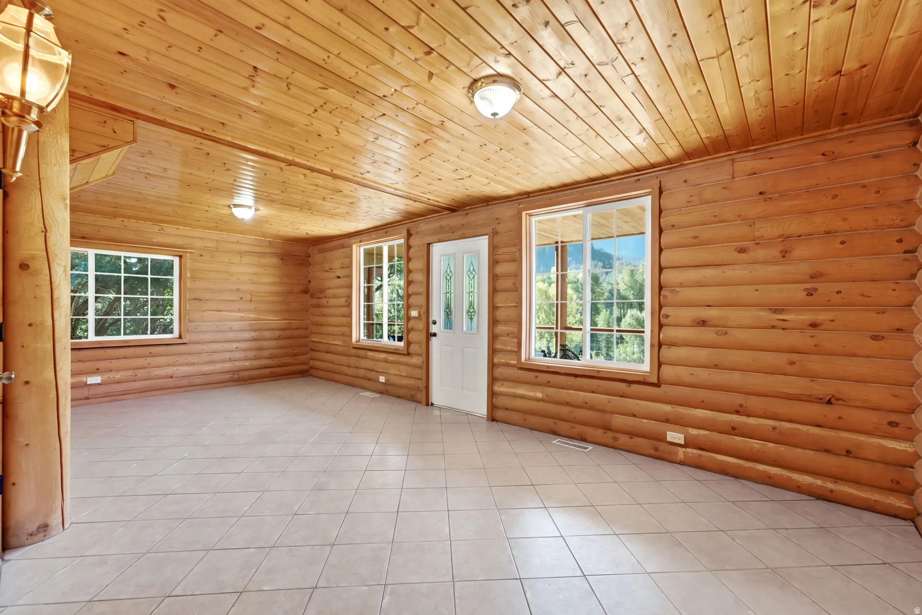 Wood-paneled walls and ceilings, recessed lighting, multiple windows, and a tiled floor