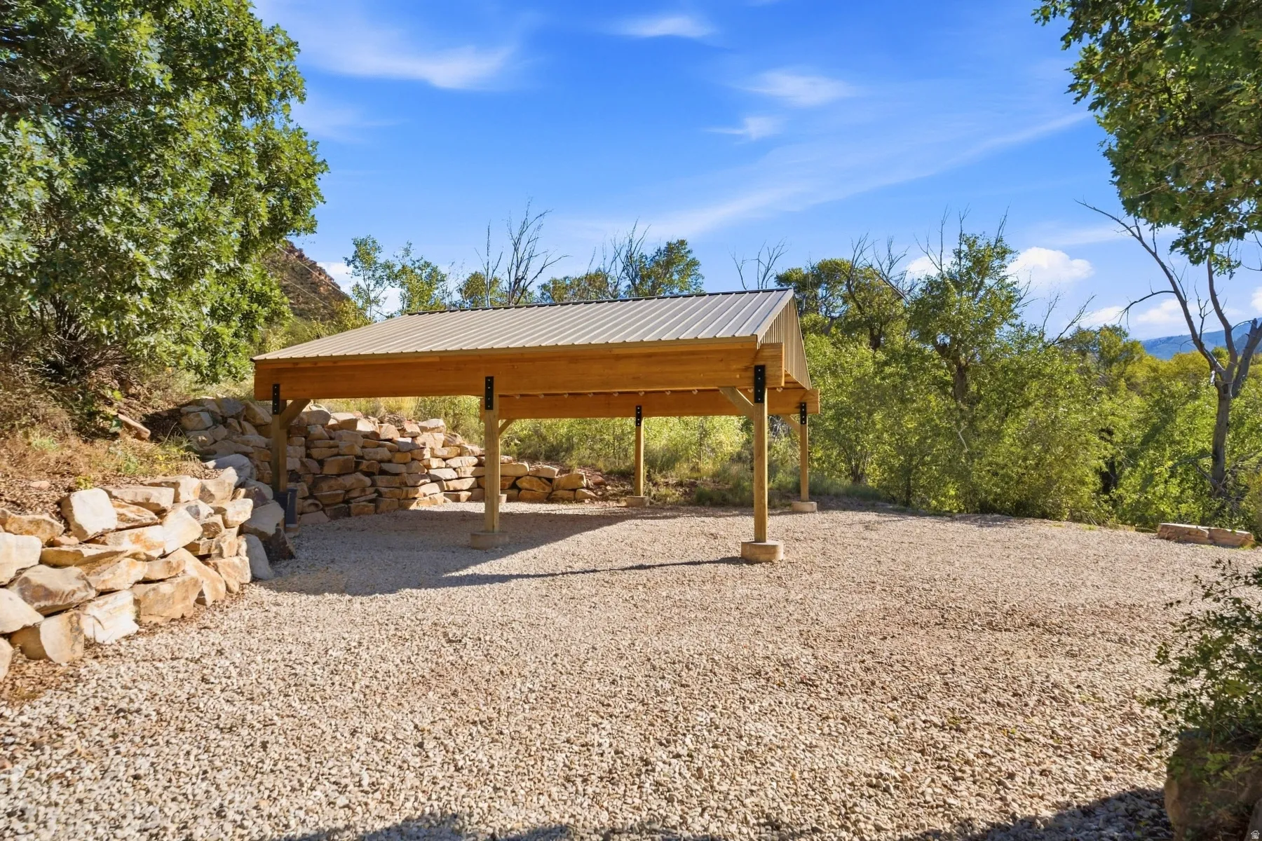 Gravel parking area featuring a wood-frame carport with a metal roof