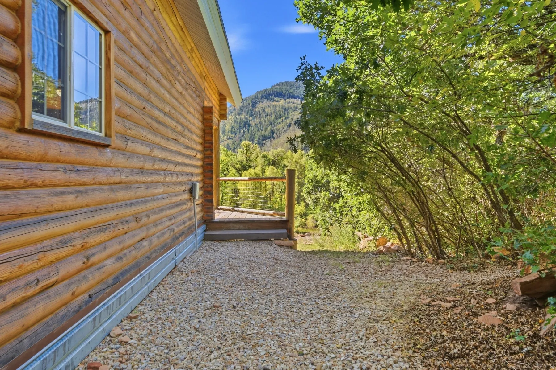 Log-sided exterior with a light-toned window frame and a gravel-covered ground surface