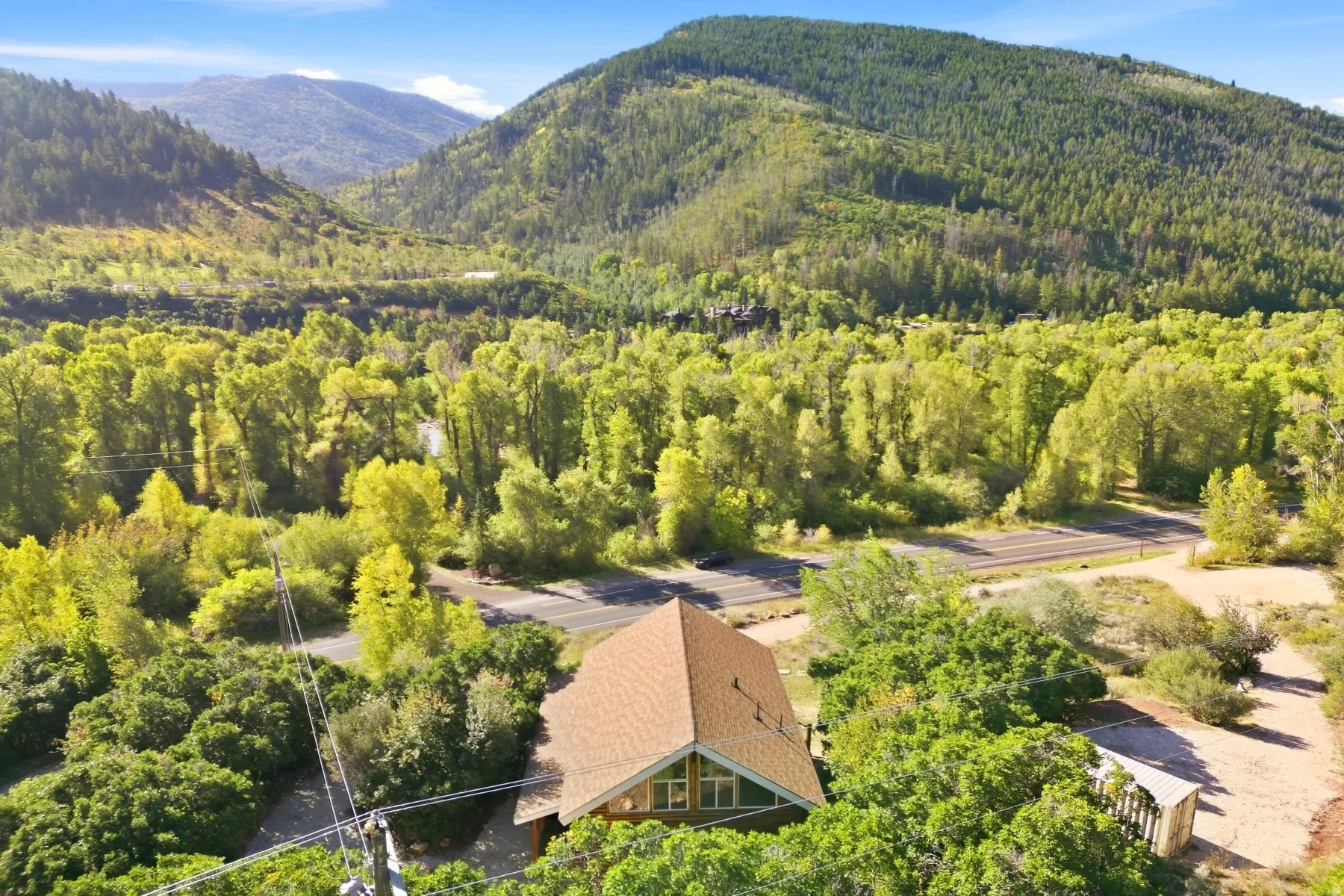Gabled roofline property surrounded by mature trees, with a prominent mountain backdrop