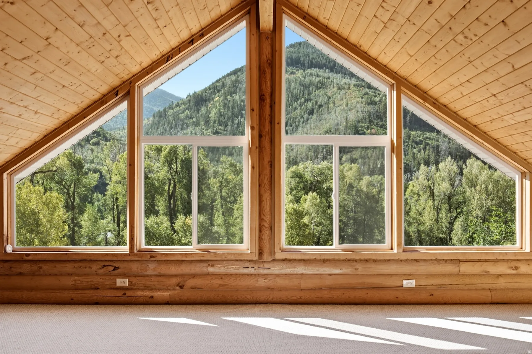 Vaulted wood-paneled ceilings, natural wood walls, and triangular architectural windows framing mountainous scenery