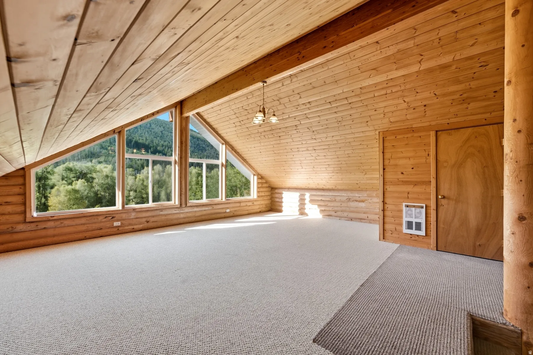 Expansive room featuring natural wood paneling, exposed wood beams, and a vaulted ceiling