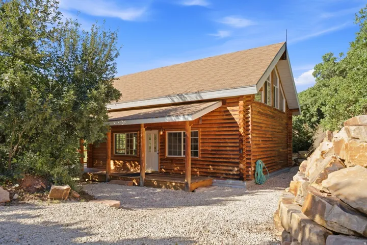 Wood-sided residence featuring a covered porch, an A-frame roofline, and natural rock landscaping