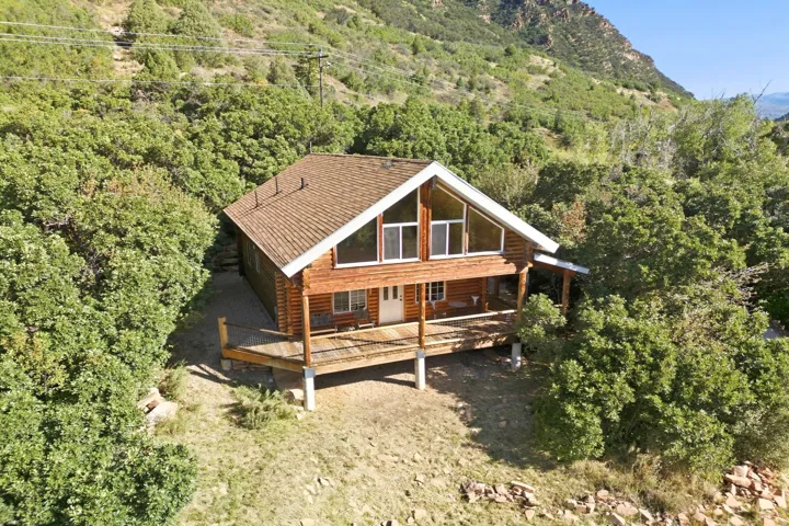 Log cabin exterior with a pitched roof, expansive front deck, and a wall of windows