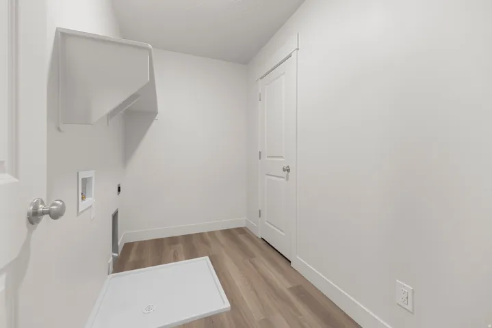 Laundry area with wood-finish flooring, white walls, and built-in shelving