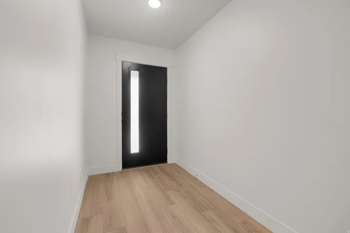 Entryway featuring a contemporary black door with vertical privacy glass, wood-finish flooring, and recessed ceiling lighting