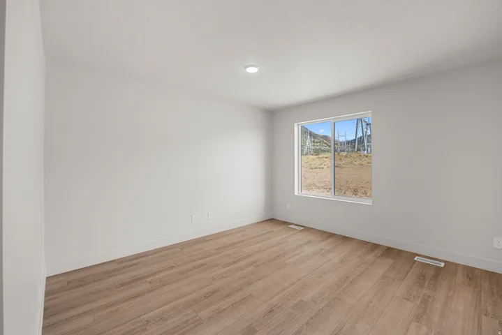 Recessed ceiling lighting, wood-finish flooring, white trim, and a window with a mountain backdrop