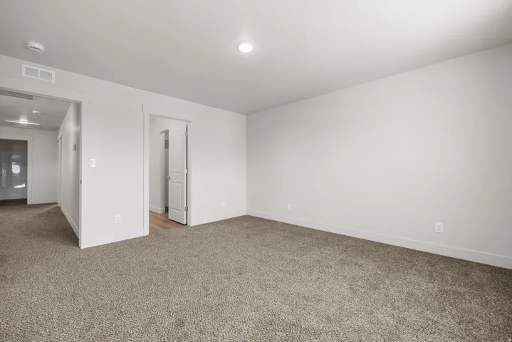 Neutral-toned carpeting, white walls, recessed lighting, and a white interior door