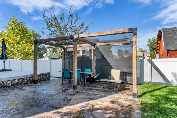 Stamped concrete patio with a wooden pergola featuring a shade screen