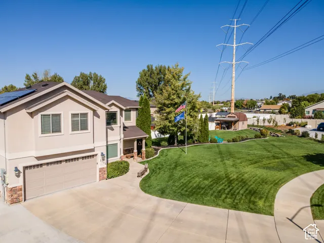 Stucco exterior residence featuring a two-car garage, solar panels, and a concrete driveway