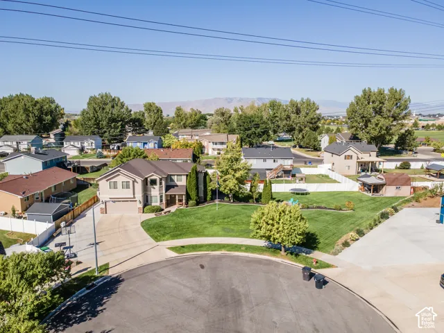 Two-story residence with an attached garage, expansive front lawn, paved driveway, and mature landscaping