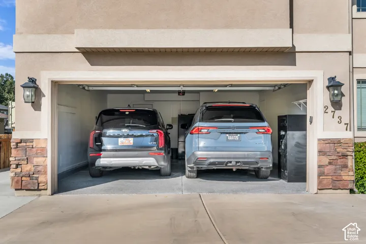 Two-car garage with epoxy flooring, integrated shelving, and stone veneer accents