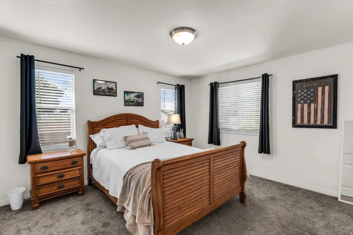 Carpeted flooring, three windows with blinds, and an overhead light fixture