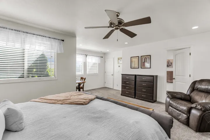 Expansive room featuring multiple windows with horizontal blinds, neutral carpeting, a ceiling fan with integrated lighting, and recessed ceiling lights