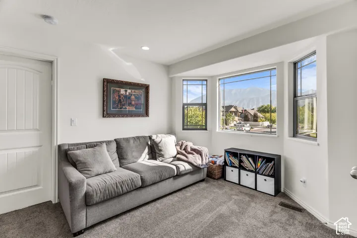 Bay window with multiple panes, recessed lighting, white interior door, and wall-to-wall carpeting