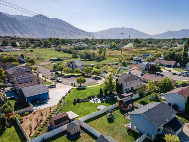 Expansive residential property with a detached blue garage, a large manicured lawn, and multiple storage sheds