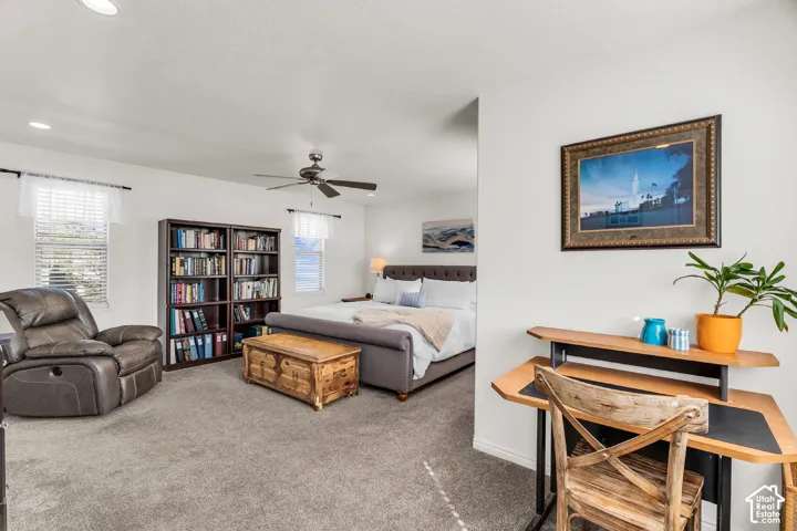 Carpeted room with recessed lighting, ceiling fan, and multiple windows with blinds