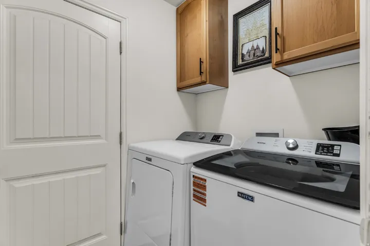 Laundry area with white paneled door, light-toned wall cabinetry, and white walls