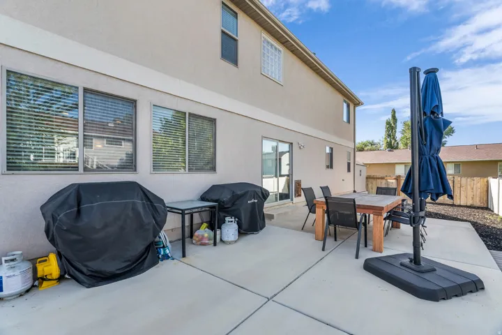 Expansive concrete patio with direct access via a sliding glass door, featuring a stucco exterior and multiple windows